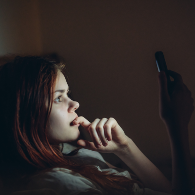 woman staring at phone screen in the dark