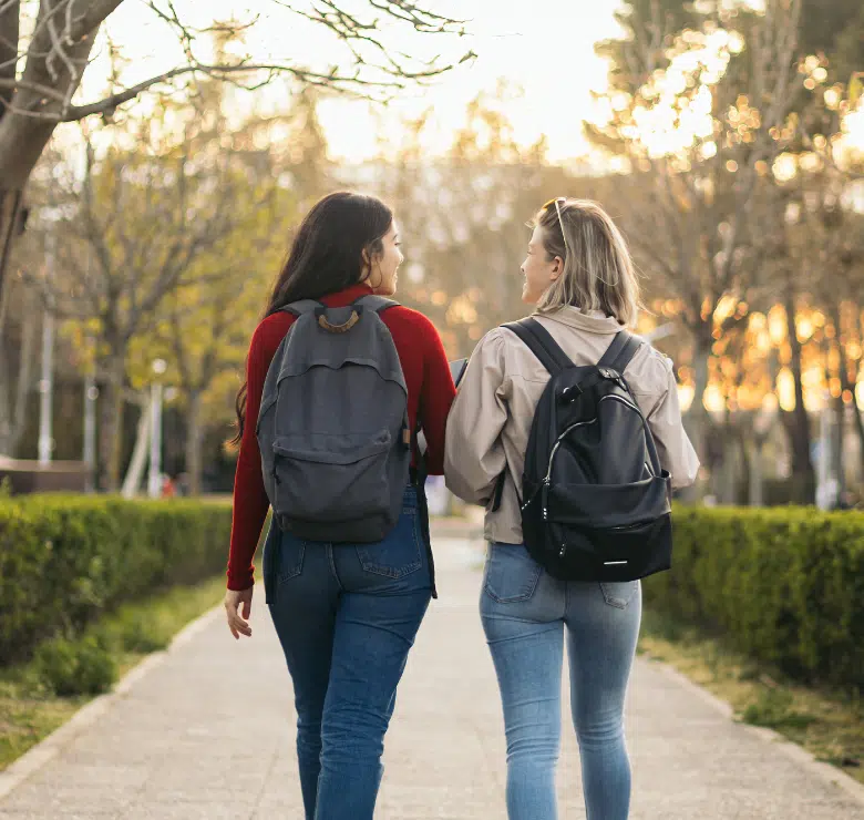 two women walking on college campus pathway