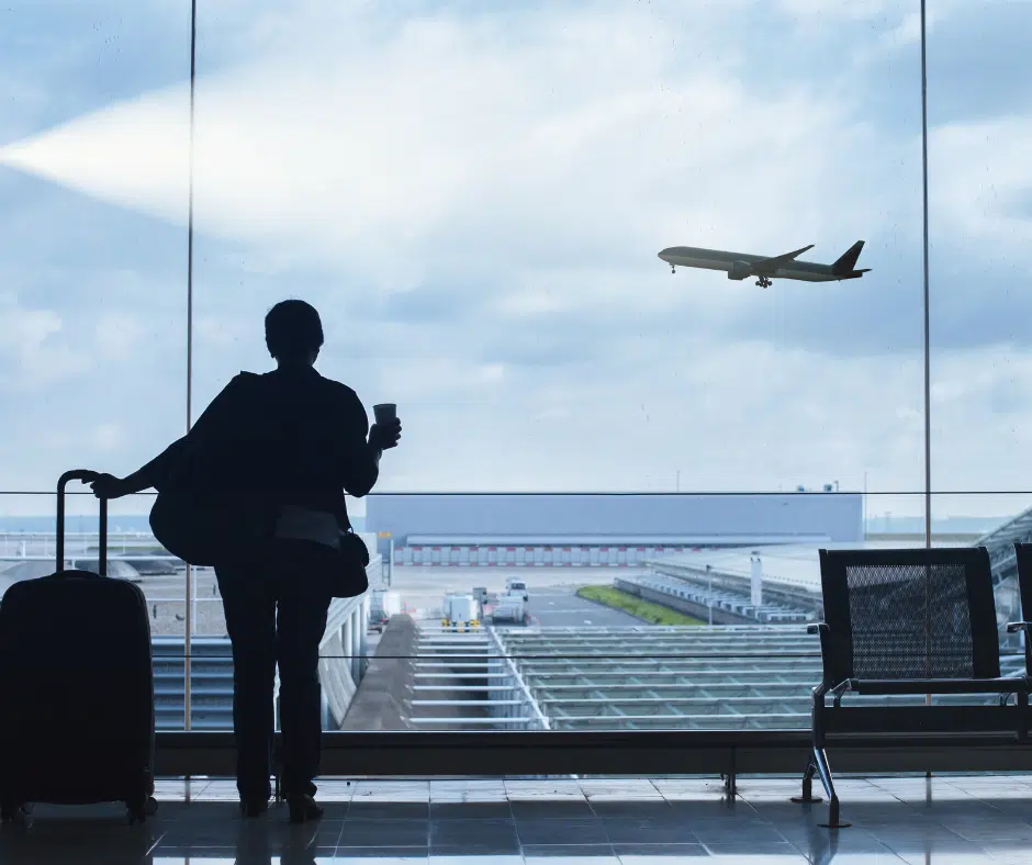 Woman looking out the airport window at a plane taking off
