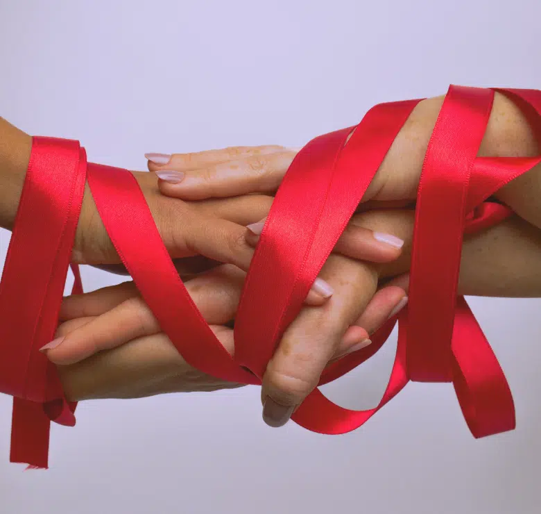 womens hands draped in red ribbon