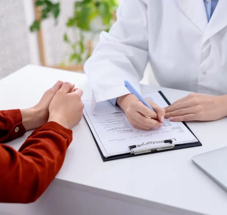 doctor talking to patient at a desk and with a clip board